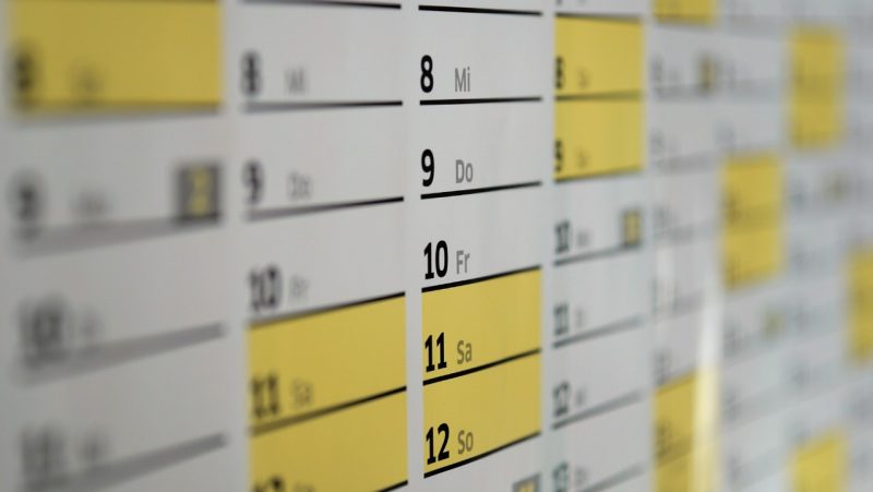 glossy wall calendar in table format. Saturdays and Sundays highlighted in yellow.